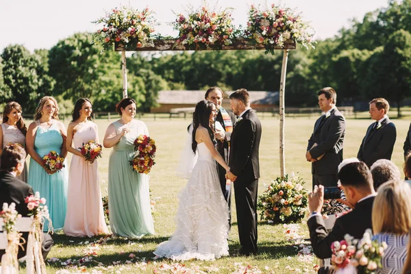 Sposa e sposo si tengono le mani in piedi davanti a un sacerdote d — Foto Stock