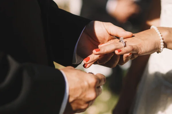 El novio pone un anillo de bodas sobre el dedo de la novia sosteniéndolo tierno — Foto de Stock
