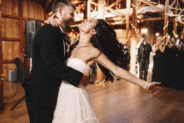 Bruden skakar sitt mörka hår när man dansar med en groom i trä — Stockfoto