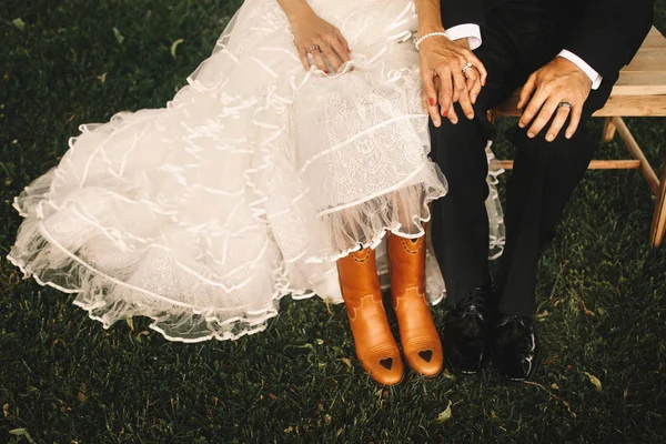 Piedi della sposa in stivali di pelle cowboy stare dietro lacque dello sposo — Foto Stock