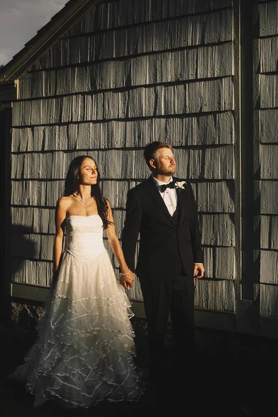 Evening sun illuminates cheerful wedding couple standing before — Stock Photo, Image