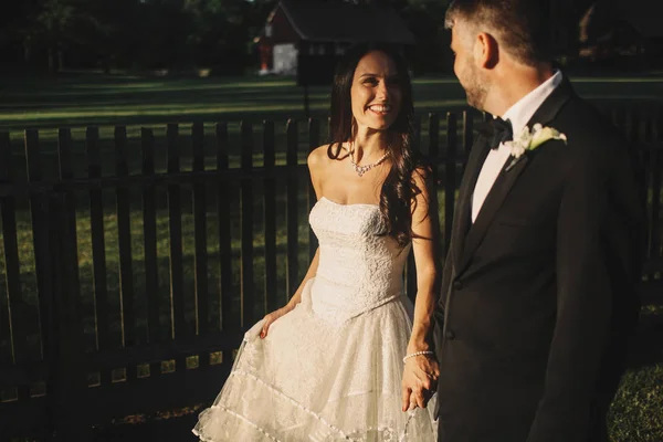 Glückliche Braut blickt einen Bräutigam an, während er Hand in Hand mit ihm geht — Stockfoto