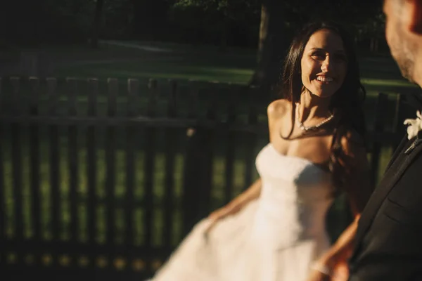 Linda noiva sorri para um noivo enquanto está em pé diante de uma madeira — Fotografia de Stock