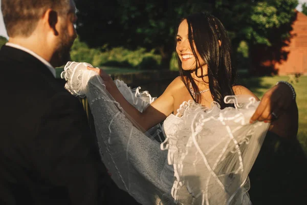 Noiva levanta seu vestido como asas enquanto está de pé diante de um groo — Fotografia de Stock