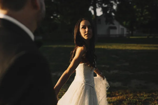 Sun illumiantes half of bride's face while she turns to a groom — Stock Photo, Image