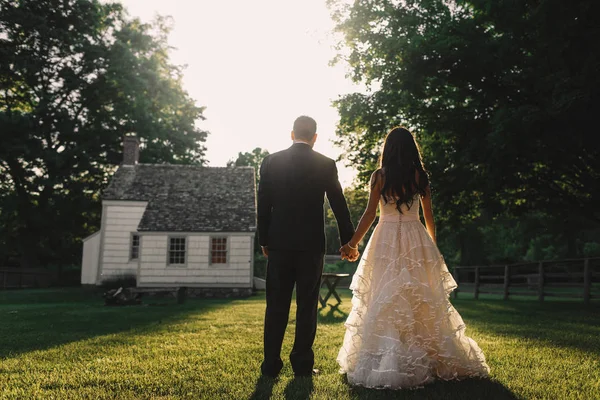 Nevěsta a ženich sledovat západ slunce nad malý bílý dům — Stock fotografie