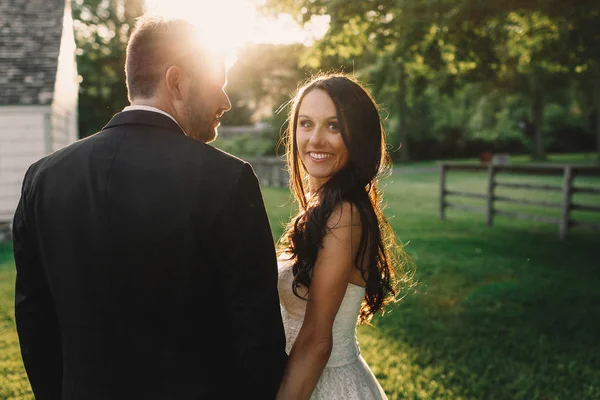 Surprised bride looks over groom's shoulder while standing on th — Stock Photo, Image