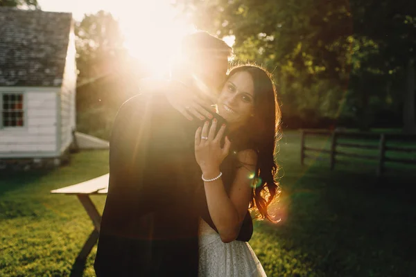 Bright sun shines over the groom kissing bride's cheek — Stock Photo, Image