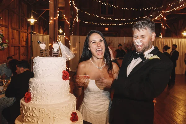 Γαμπρός με το πρόσωπο στην γαμήλια τούρτα περίπτερα πίσω από μια νύφη — Φωτογραφία Αρχείου