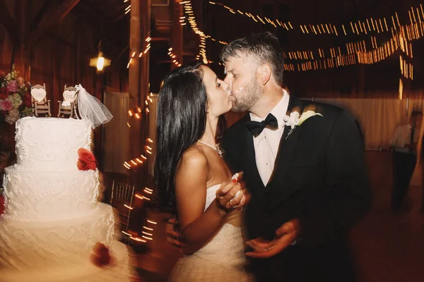 Noivo beijos rosto da noiva coberto com esmalte de bolo de casamento — Fotografia de Stock