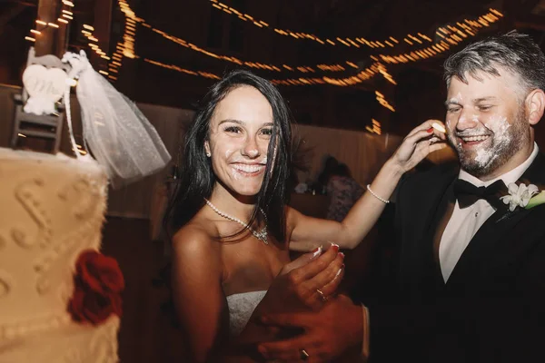面白い花嫁が結婚式で彼の顔を覆っている新郎の前に立っています。 — ストック写真