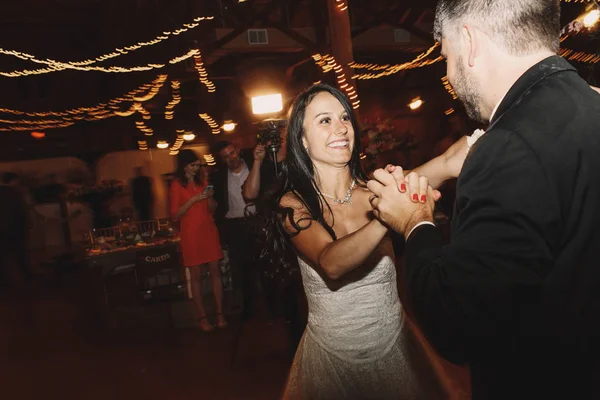 Bruidegom strekt zich uit van bruid handen whiel haar dansen in de nacht-hal — Stockfoto