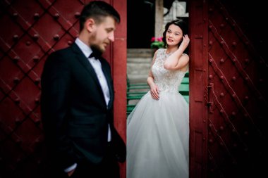 Gelin Damat kırmızı kapı arkasından bakar 