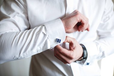 Damat mavi kol düğmeleri forması koyar. 