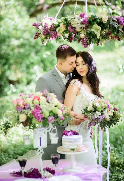 幸福的新婚夫妇站在紫罗兰色的装饰跟同桌吃饭 — 图库照片