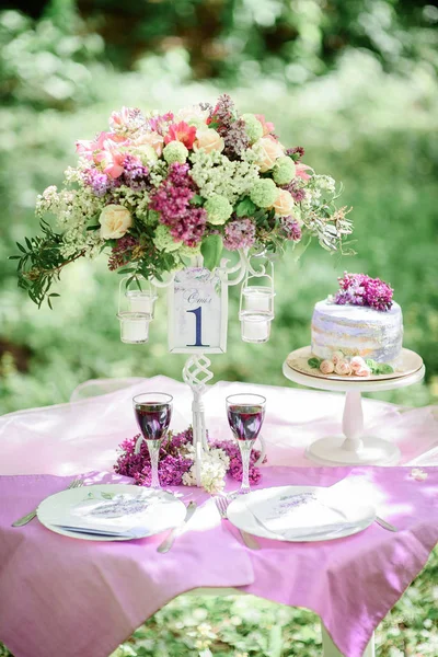 Table number one with bouquet of violet flowers and little cake