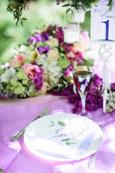 Üveg borral állni a lila díszítésű asztalnál — Stock Fotó