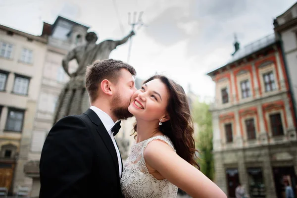 Весільна пара цілується перед статуєю в центрі міста — стокове фото