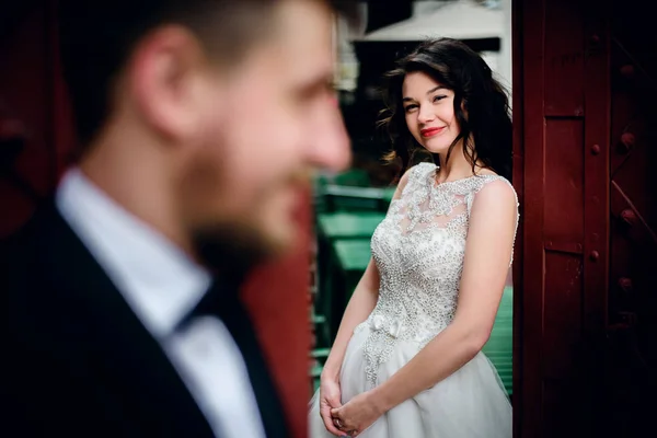 Braut blickt Bräutigam hinter roten Toren an — Stockfoto
