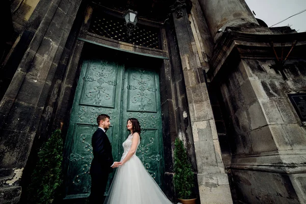 Braut und Bräutigam bewundern einander vor grüner Tür — Stockfoto