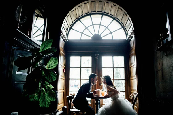 Krásné svatební pár sedí u stolku v kavárně — Stock fotografie