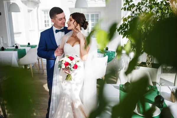 Посмотрите сквозь зелень на свадебную пару, стоящую в холле — стоковое фото