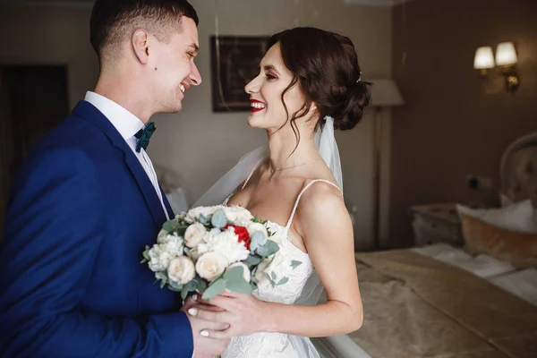 Nevěsta a ženich úsměv na sebe stojící v místnosti — Stock fotografie
