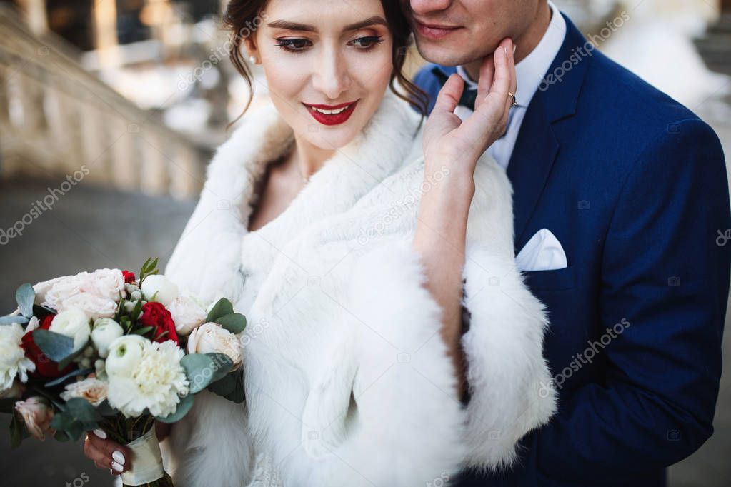 Groom hugs bride from behind posing in the winter city 