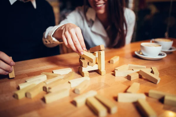At the coffee shop hands on the table folded puzzle. Play jenga on the table, wooden tol, couple plays — Stock Photo, Image