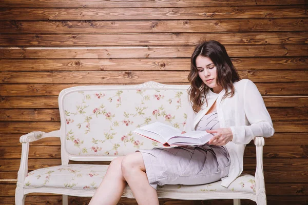 Menina em roupas brancas em um banco com um livro — Fotografia de Stock