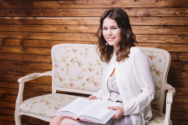 Chica en ropa blanca en un banco con un libro —  Fotos de Stock