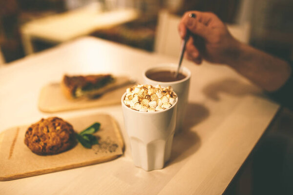 Cocoa with marshmallows and cake on the table. Hand mixed drink — Stock Photo, Image