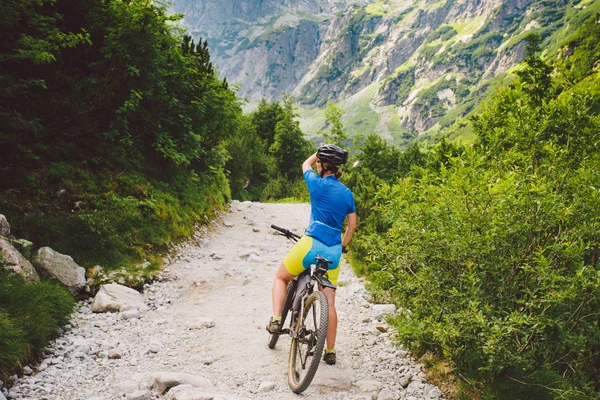 Dziewczyna na rowerze jedzie na Słowację. czarny hełm, niebieska koszula, góry, Tatry Wysokie, — Zdjęcie stockowe