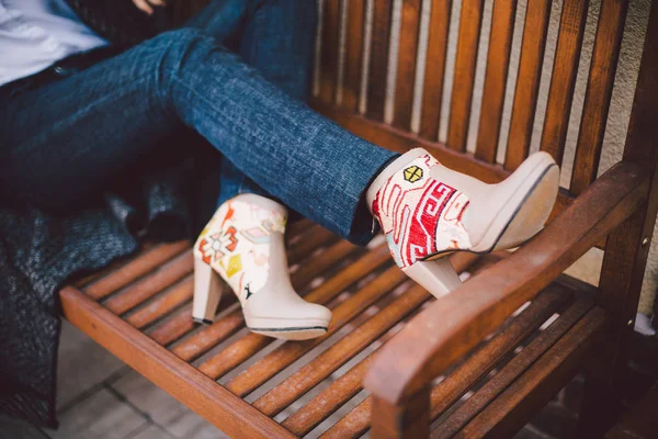 Filles pieds en bottes en cuir beige avec broderie sur un banc en bois — Photo