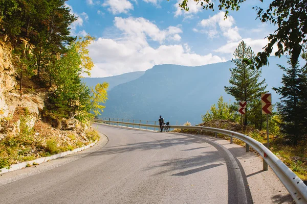 Un bărbat stă lângă o bicicletă pe drumul de munte. Vara în munții Bulgariei — Fotografie, imagine de stoc