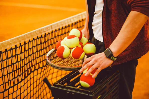 Omul de mână ține o rachetă de tenis și o mulțime de goluri. Coș pentru mingi de tenis , — Fotografie, imagine de stoc