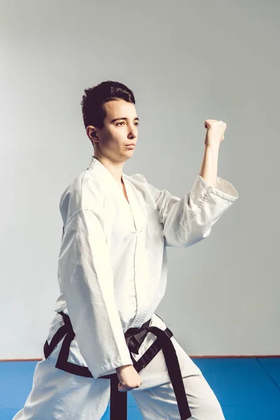 Chica, Taekwondo es marcial Stoke manos en puños, enfocado, mirada seria en el estudio sobre fondo aislado gris — Foto de Stock