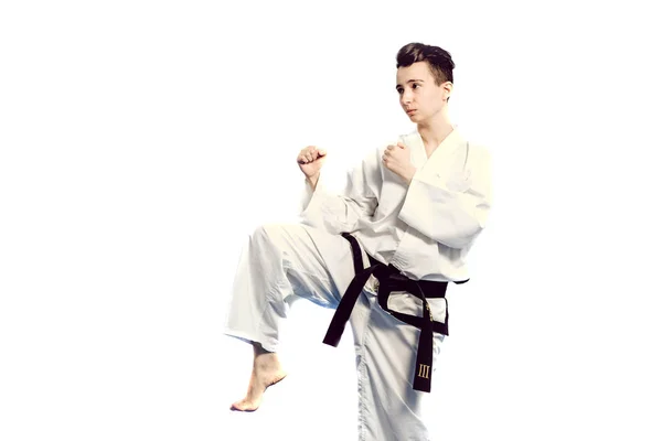 Ragazza in costume da karate kimono in studio su sfondo grigio. Femmina bambino mostra stan judo o karate in uniforme bianca con cintura nera. Sport individuale di arti marziali. ritratto del corpo — Foto Stock