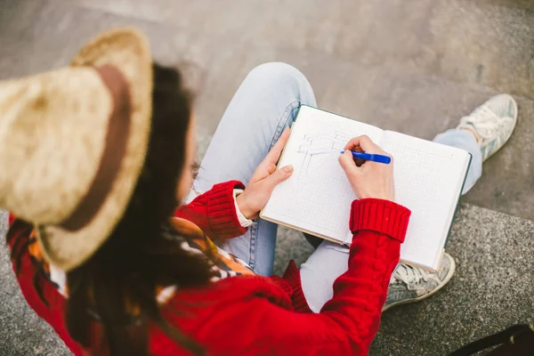 Güzel kız ile bir defter ve kalem elimde, sokakta oturan yapım notları ve kolları. — Stok fotoğraf