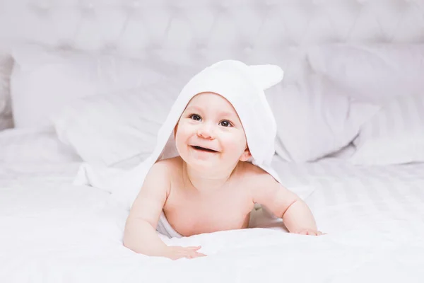 Adorablemente el bebé se acuesta sobre una toalla blanca en la cama. Feliz infancia y concepto de salud . — Foto de Stock