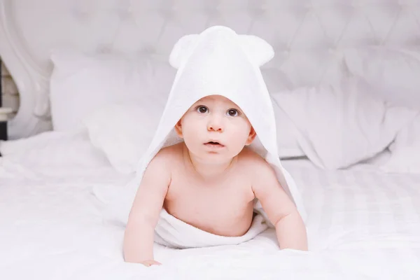 Adorablemente el bebé se acuesta sobre una toalla blanca en la cama. Feliz infancia y concepto de salud . — Foto de Stock