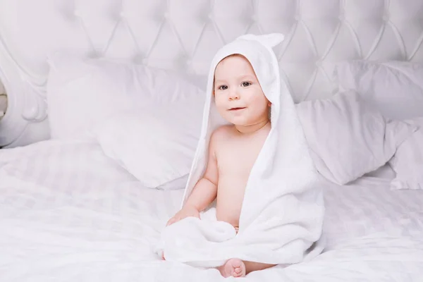 Adorablemente el bebé se acuesta sobre una toalla blanca en la cama. Feliz infancia y concepto de salud . — Foto de Stock