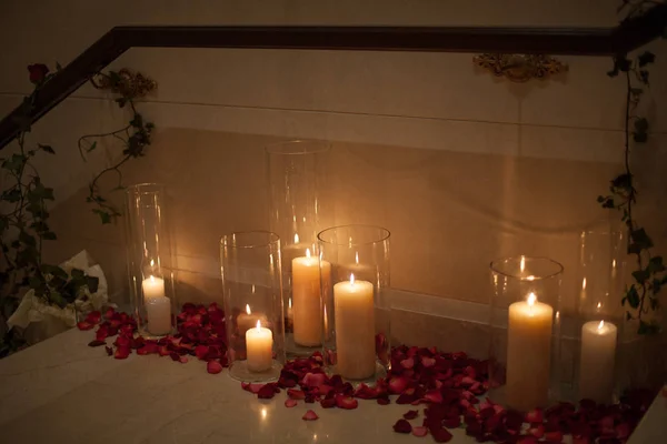 Candle surrounded by red rose petals with dreamy reflection — Stock Photo, Image
