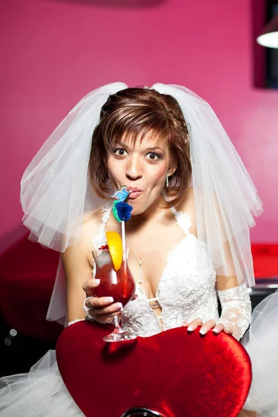 Menina bonita, a noiva com véu branco engraçado beber um coquetel de vermelho. O tubo na boca — Fotografia de Stock