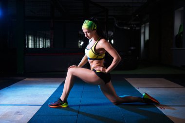 güzel, güçlü, ince, fiziksel görünüm olarak iyi spor salonunda egzersizleri yapıyor. Kısa şort ve tank top yeşil, üzerinde kafa bandaj giyinmiş.