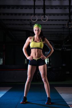 güzel, güçlü, ince, fiziksel görünüm olarak iyi spor salonunda egzersizleri yapıyor. Kısa şort ve tank top yeşil, üzerinde kafa bandaj giyinmiş.