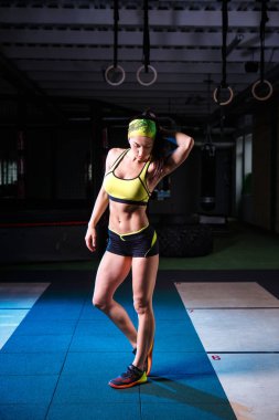 güzel, güçlü, ince, fiziksel görünüm olarak iyi spor salonunda egzersizleri yapıyor. Kısa şort ve tank top yeşil, üzerinde kafa bandaj giyinmiş.