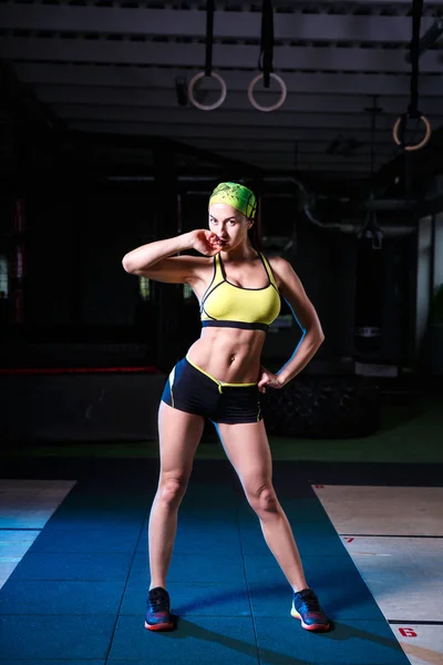 Bonito, forte, esbelto, em boa forma física no ginásio fazendo exercícios. Vestido com shorts curtos e top tanque verde, na bandagem da cabeça . — Fotografia de Stock