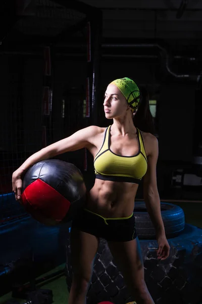 Uma rapariga forte num ginásio treina com a bola. Saúde, conceito de desporto — Fotografia de Stock