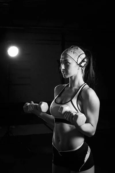 Giovane bella ragazza in palestra allena i muscoli delle mani con manubri verdi. Concetto sportivo — Foto Stock